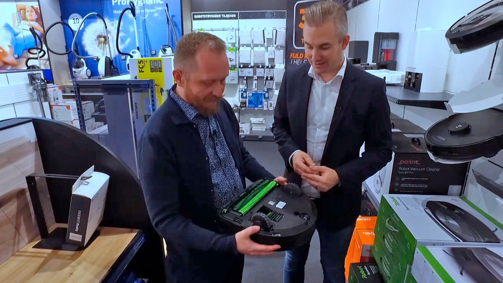 2 mænd kikker på en strådløs og batteridrevet støvsuger. De drøfter CE-mærkning og standarder i EU